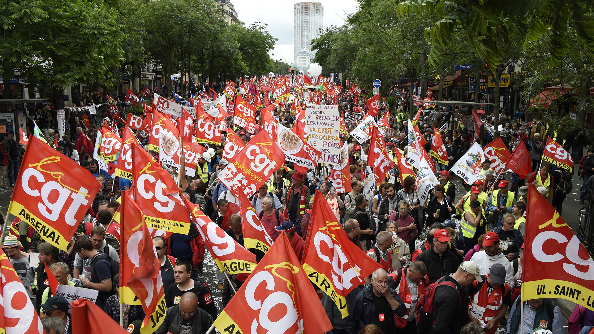 People wave flags of French union confederation Confederation generale du travail (CGT) during a demonstration against proposed labour reforms in Paris on June 14, 2016.  Strikes closed the Eiffel Tower and disrupted transport in France on June 14 as tens of thousands prepared to march against labour reforms with the Euro 2016 football championship in full swing.  / AFP PHOTO / DOMINIQUE FAGET