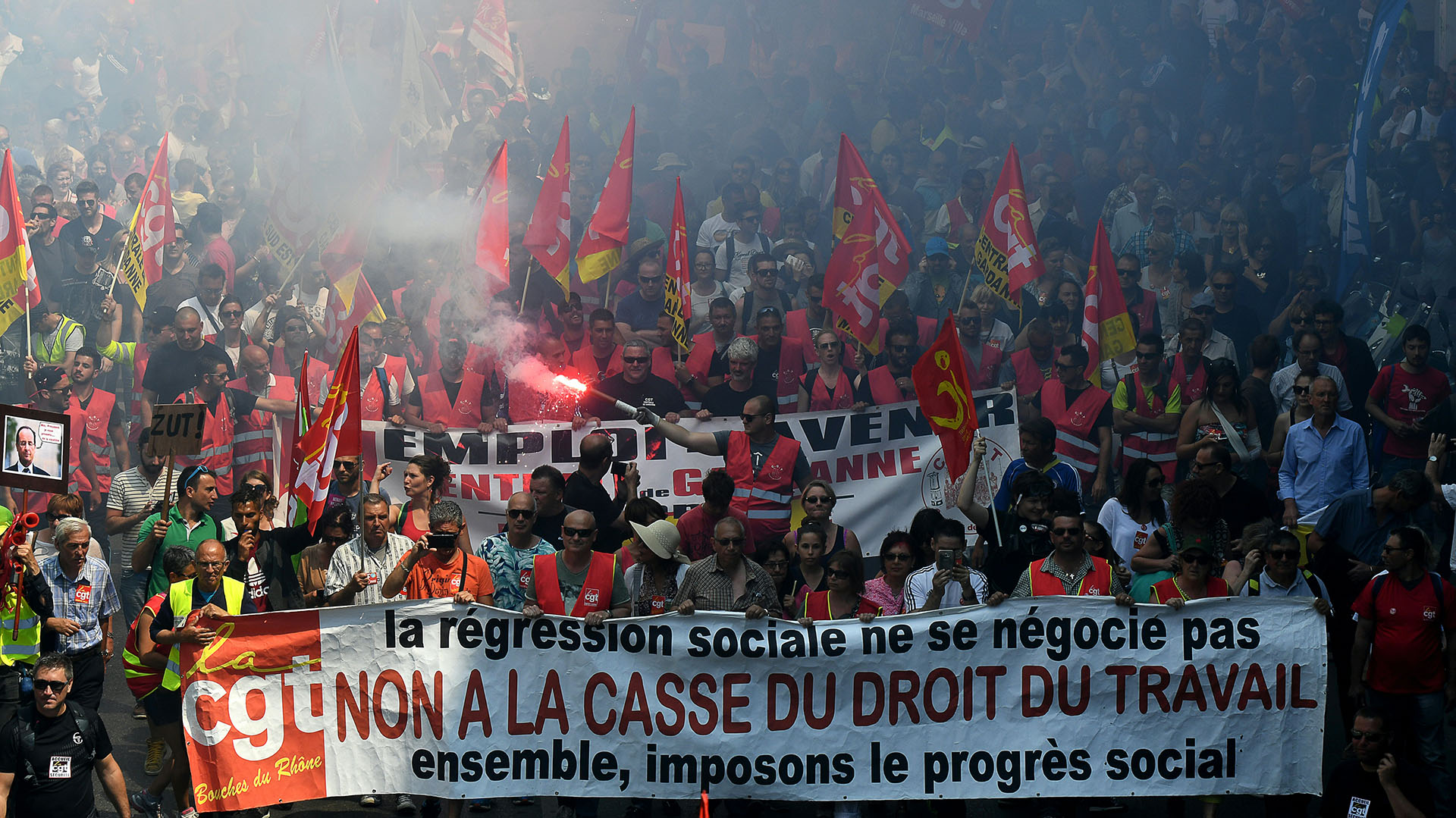 People demonstrate and hold a banner reading "No to the breaking of the labour laws" as they take part in a protest against the French government's planned labour law reforms, on June 14, 2016 in Marseille, southern France. With the Euro 2016 football tournament in full swing in France, thousands of people are expected to take to the streets on Tuesday in new protests against the government's hotly contested labour reforms. The latest in a wave of protests that began in March coincides with the start of debate in the French Senate over the reforms, which are aimed at making the job market more flexible but are seen by critics as too pro-business. / AFP PHOTO / BORIS HORVAT