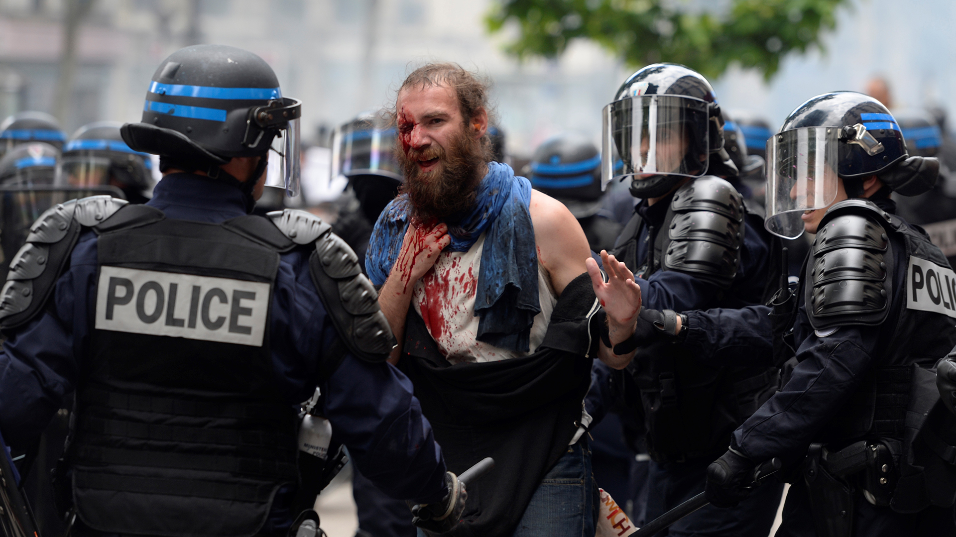 Police officers detain an injured demonstrator during a protest against the French government's planned labour law reforms, on June 14, 2016 in Paris.  The strike is the latest in months of industrial action that has seen air and rail transport severely disrupted, fuel shortages and rubbish piled up on the streets of Paris. / AFP PHOTO / ALAIN JOCARD