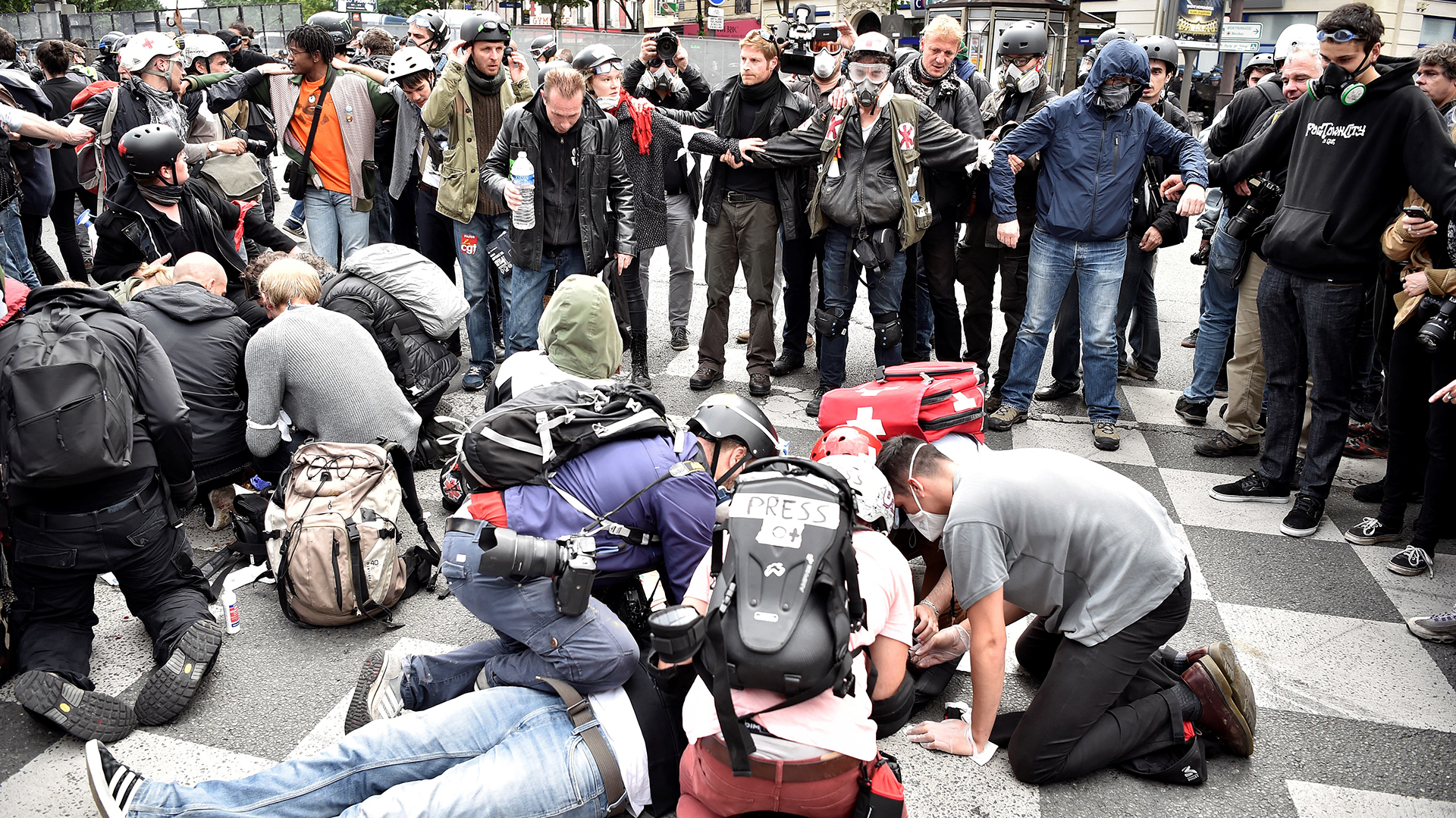 People gather around to assist an injured protester lying on the ground during a demonstration against proposed labour reforms in Paris on June 14, 2016.  Strikes closed the Eiffel Tower and disrupted transport in France on June 14 as tens of thousands prepared to march against labour reforms with the Euro 2016 football championship in full swing.  / AFP PHOTO / ALAIN JOCARD