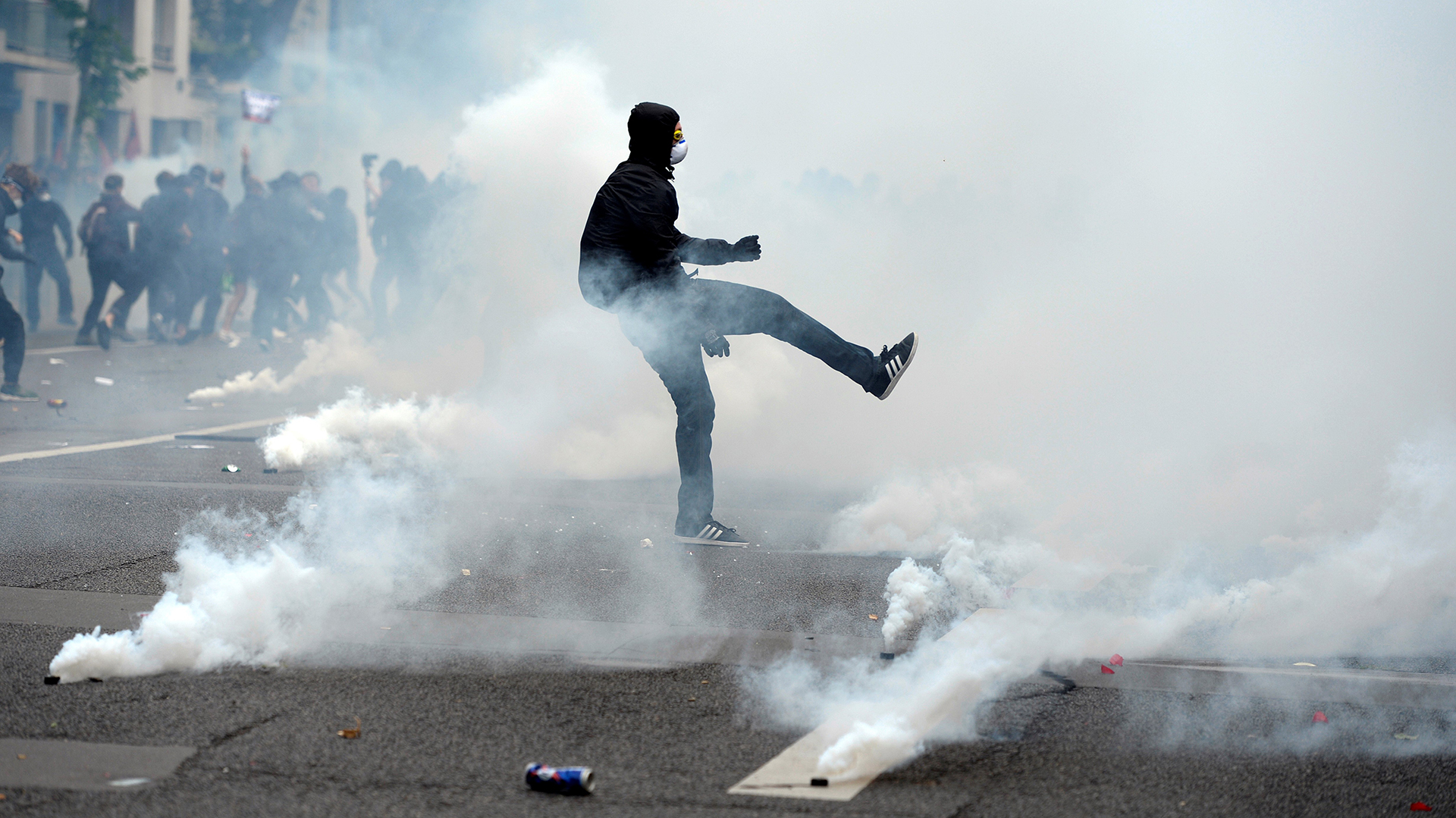 A demonstrator kicks back a tear gas canister during a protest against proposed labour reforms in Paris on June 14, 2016.  Strikes closed the Eiffel Tower and disrupted transport in France on June 14 as tens of thousands prepared to march against labour reforms with the Euro 2016 football championship in full swing.  / AFP PHOTO / ALAIN JOCARD