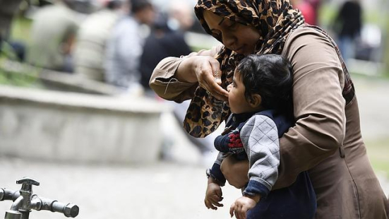 Mujer-le-da-de-beber-a-un-niño-en-Berlin