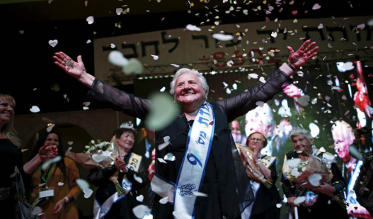Rita Berkowitz, 83, a Holocaust survivor and winner of a beauty contest for survivors of the Nazi genocide, waves on a stage, in the northern Israeli city of Haifa, November 24, 2015. Thirteen women took part in the third annual beauty contest for Holocaust survivors in Israel on Tuesday.  REUTERS/Amir Cohen